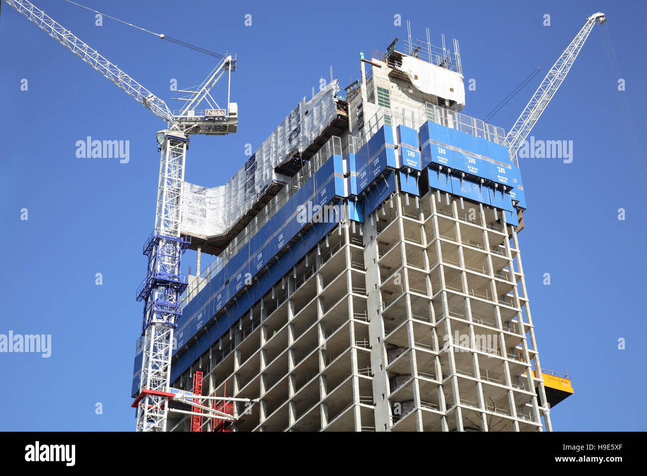 Costruzione di un nuovo e concreto incorniciato a torre nel centro di Londra, Regno Unito. Mostra gru a torre e le arrampicate, schermi di protezione. Foto Stock