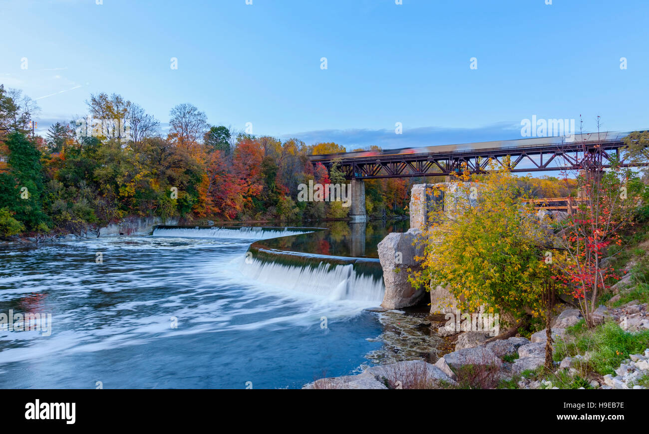 Penman la diga lungo il gran fiume con un treno che passa lungo il ponte del treno a Parigi, Brant County, Ontario, Canada. Foto Stock