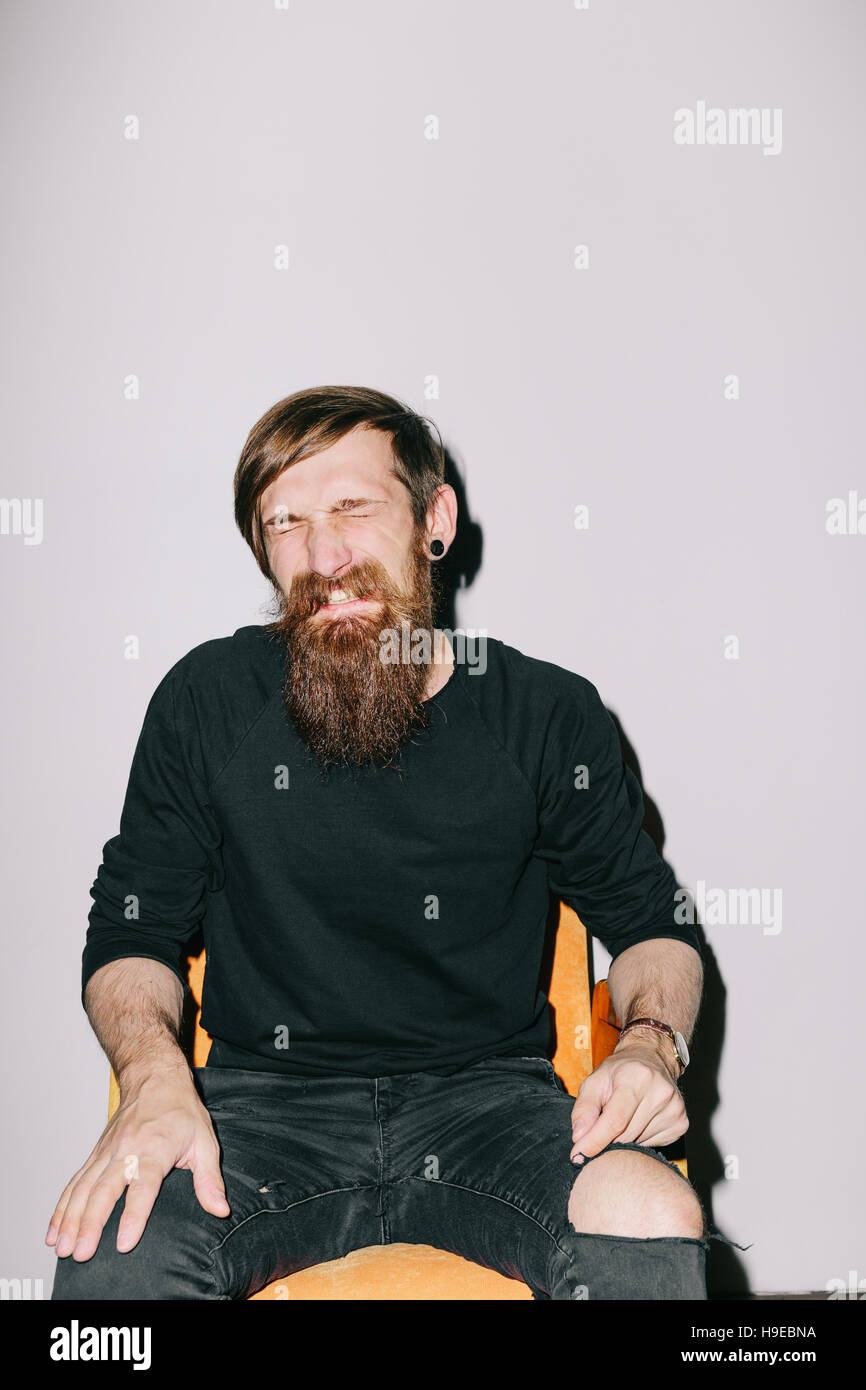 Barbuto uomo seduto in poltrona Foto Stock