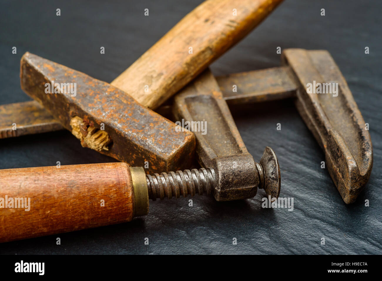 Vecchio e ben utilizzati a mano martello quadrato corto con manico in legno e il lato morsetto a vite su sfondo scuro. Foto Stock