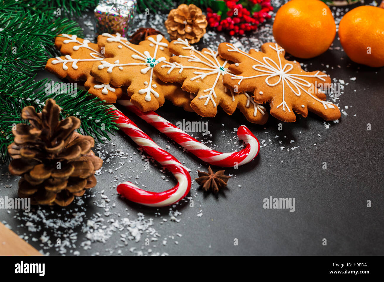 Biscotti di Natale con caramelle, cono di pino, abete e mandarini addobbati con neve Foto Stock