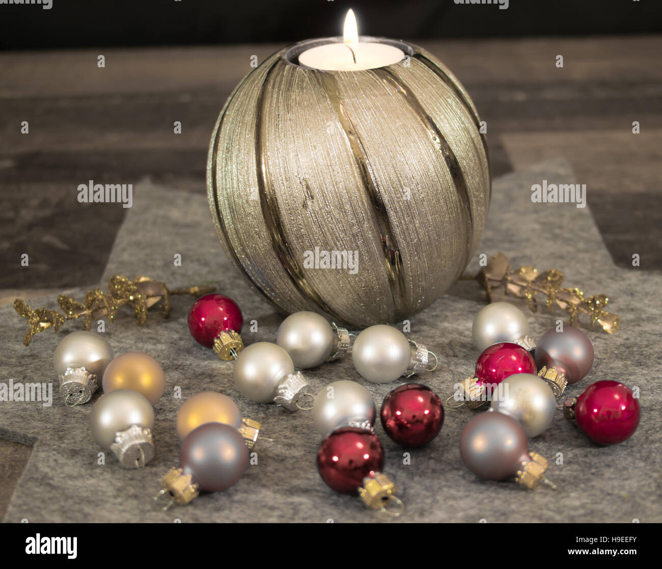 Candela che brucia con un ramo di pino, colorate palle di Natale e stelle su una tovaglia bianca. Foto Stock