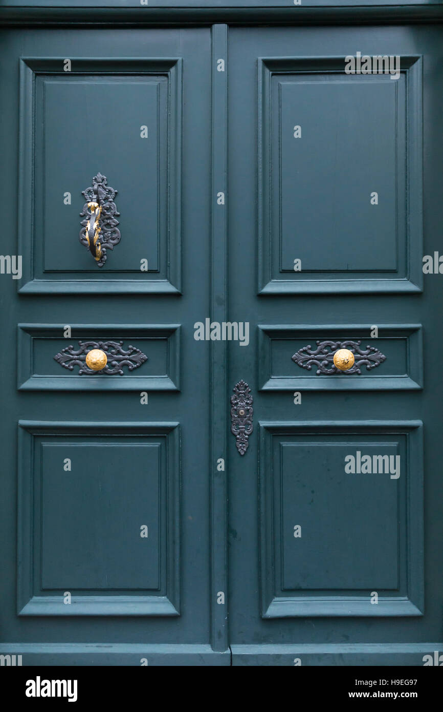 Un verde scuro di legno verniciato di uno sportello di una villa con eleganti decorazioni in metallo, golden manopole e respingente. Foto Stock