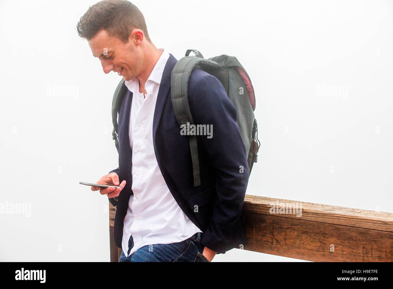 Uomo caucasico indossando uno zaino sms sul cellulare Foto Stock