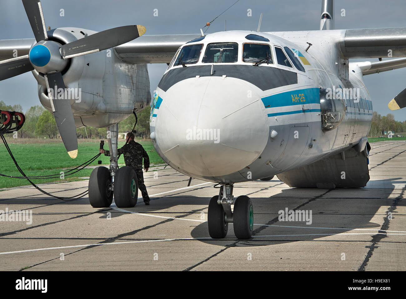 Vasilkov, Ucraina - 24 Aprile 2012: Ucraina Air Force Antonov un-26 cargo aereo si appresta ad avviare il motore con il motorino di avviamento veicolo sull'airf Foto Stock