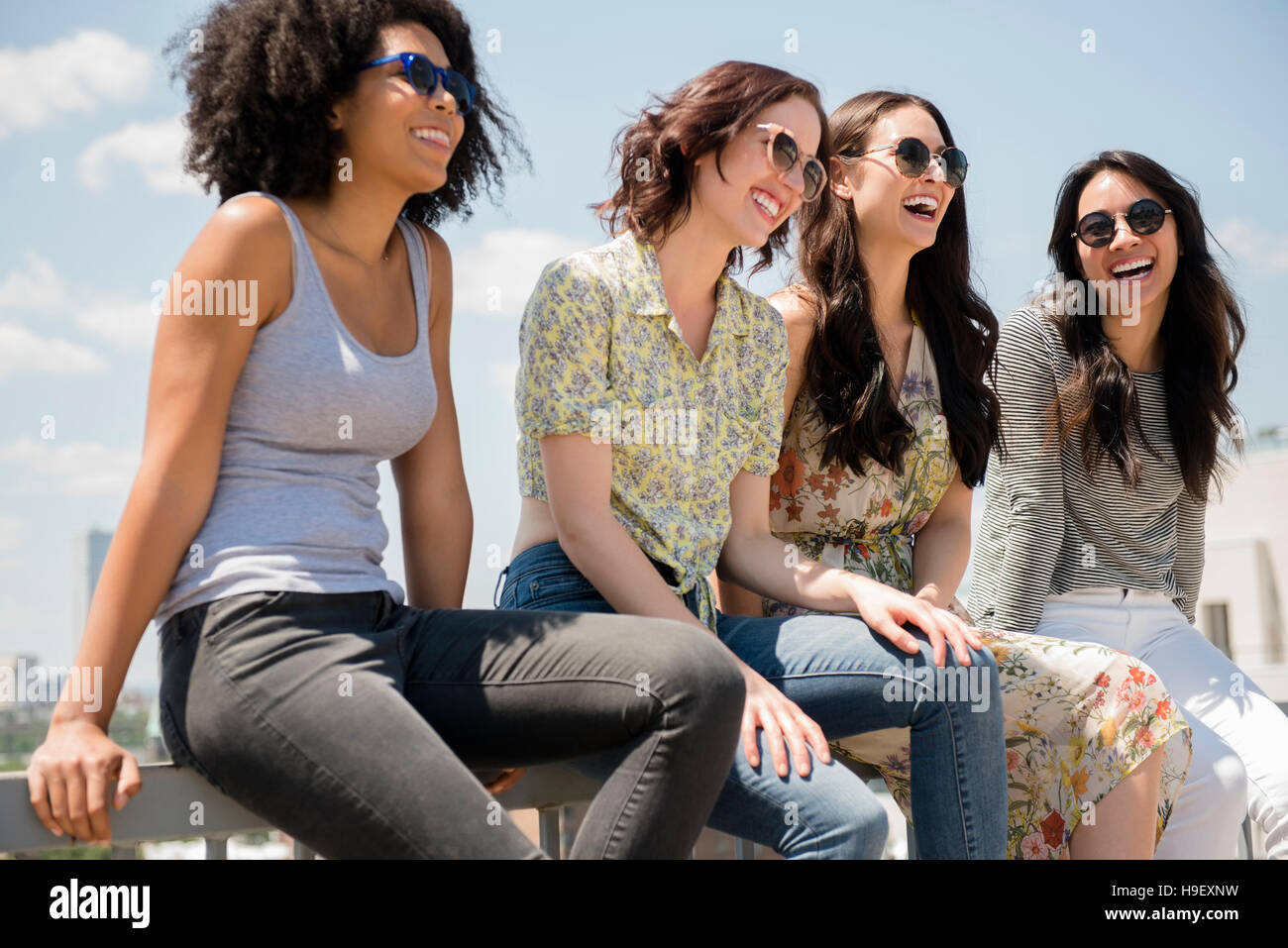Donne che ridono seduti sulla ringhiera all'aperto Foto Stock
