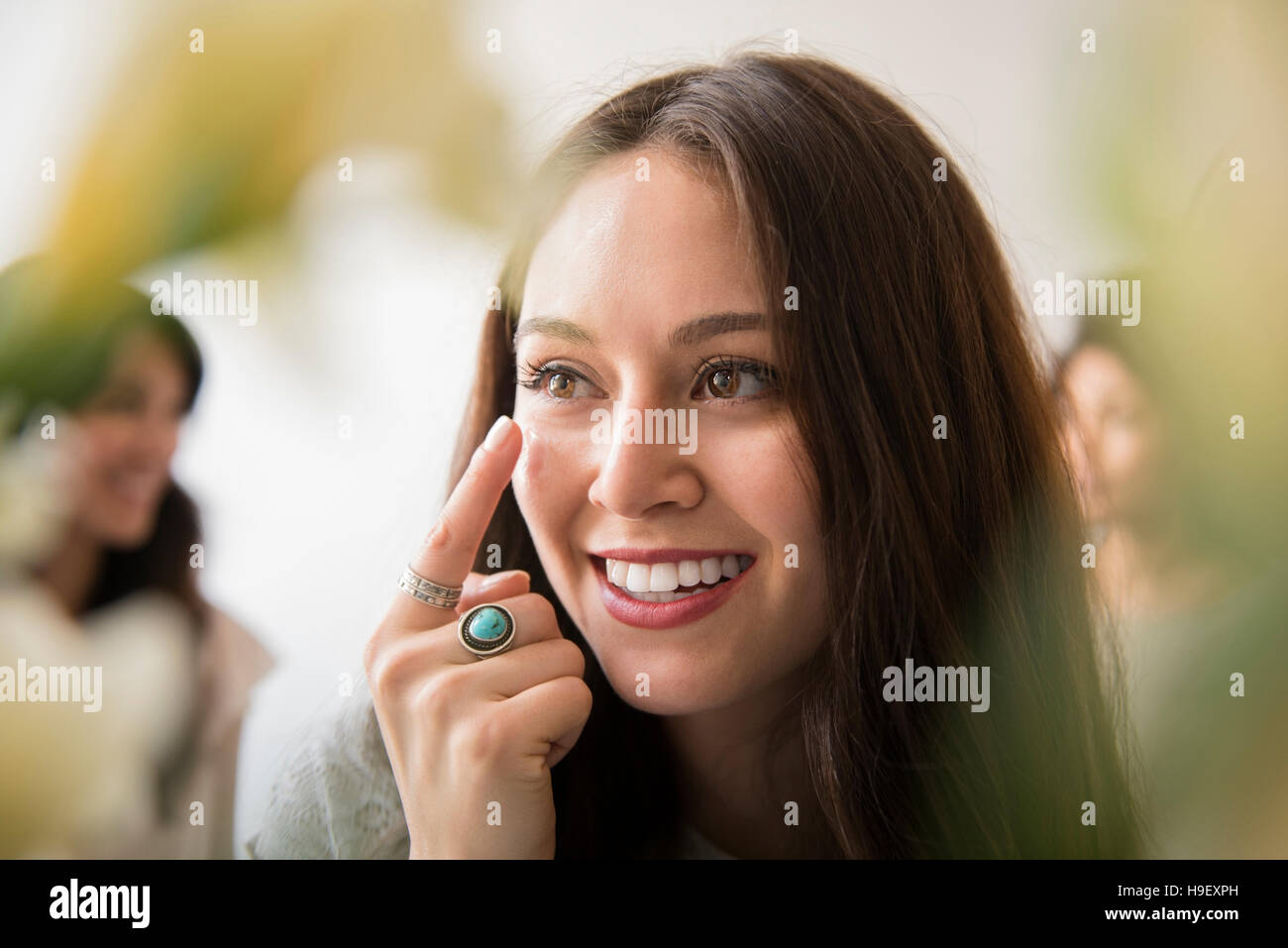 Donna sorridente applicando idratante viso Foto Stock