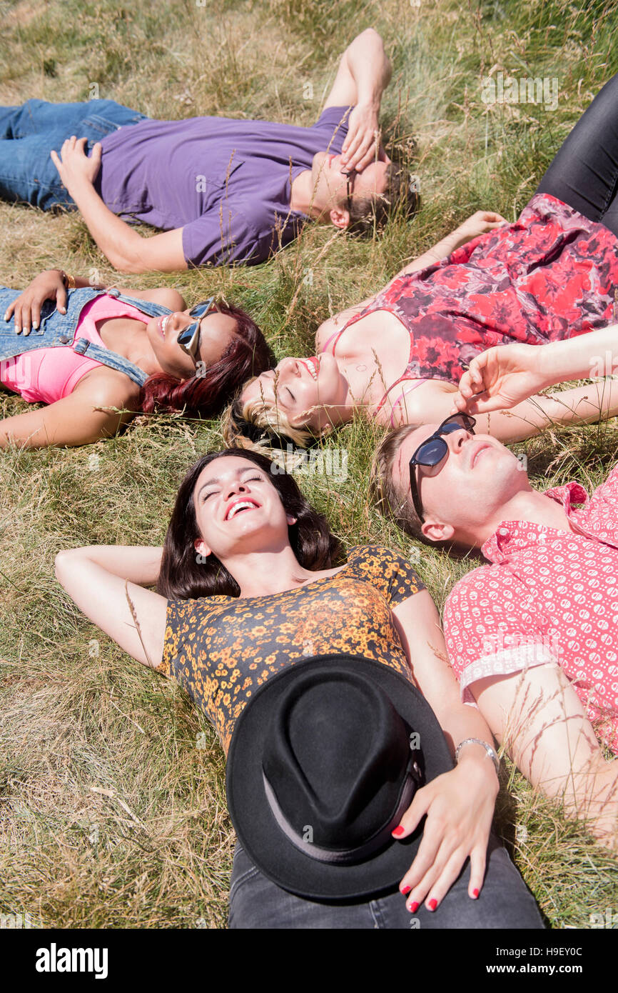 Sorridente amici rilassante nella soleggiata campo in erba Foto Stock