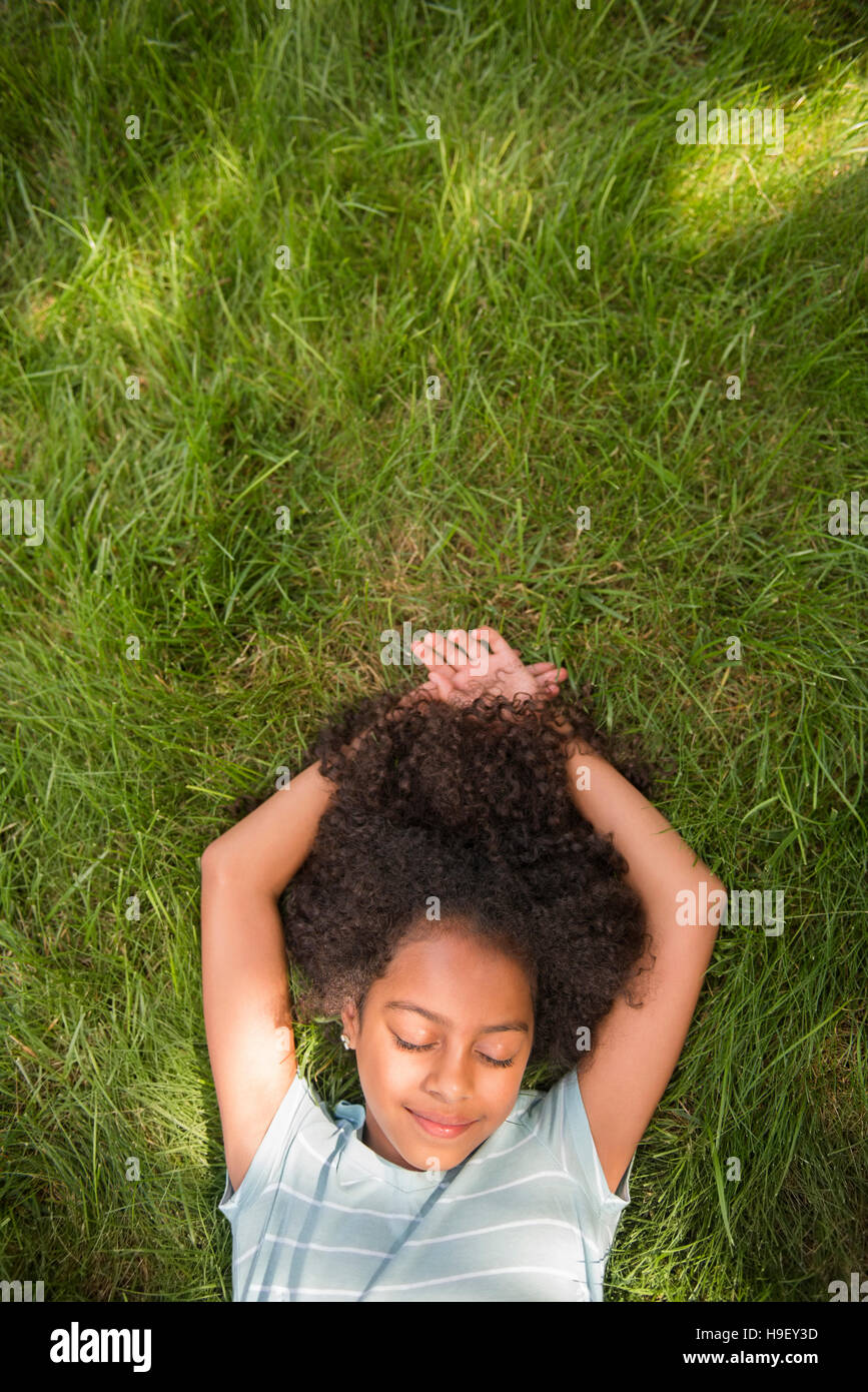 Sorridente ragazza ispanica posa in erba Foto Stock