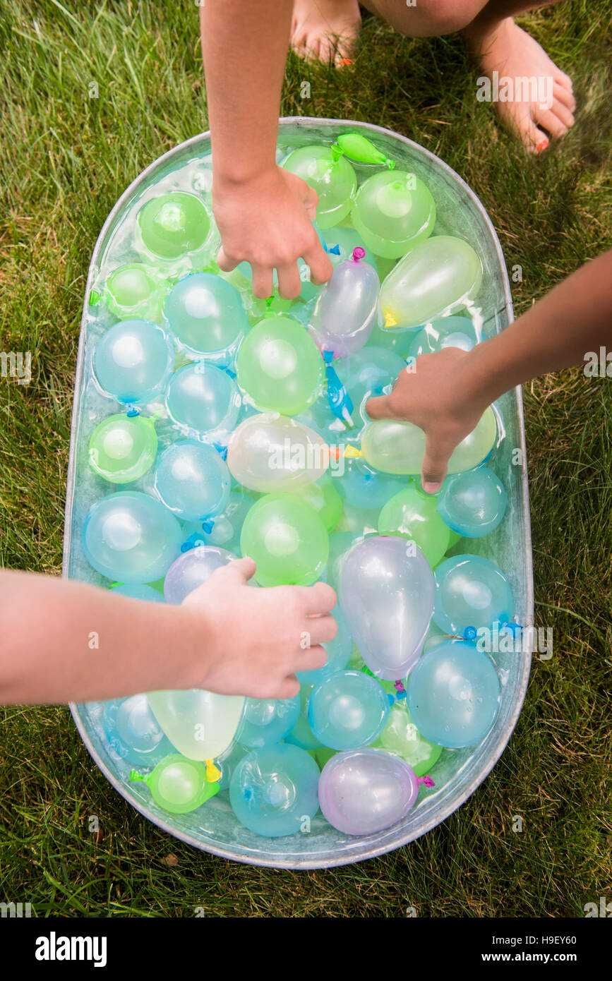 Le mani di ragazze raggiungono per palloncini di acqua in vasca Foto Stock