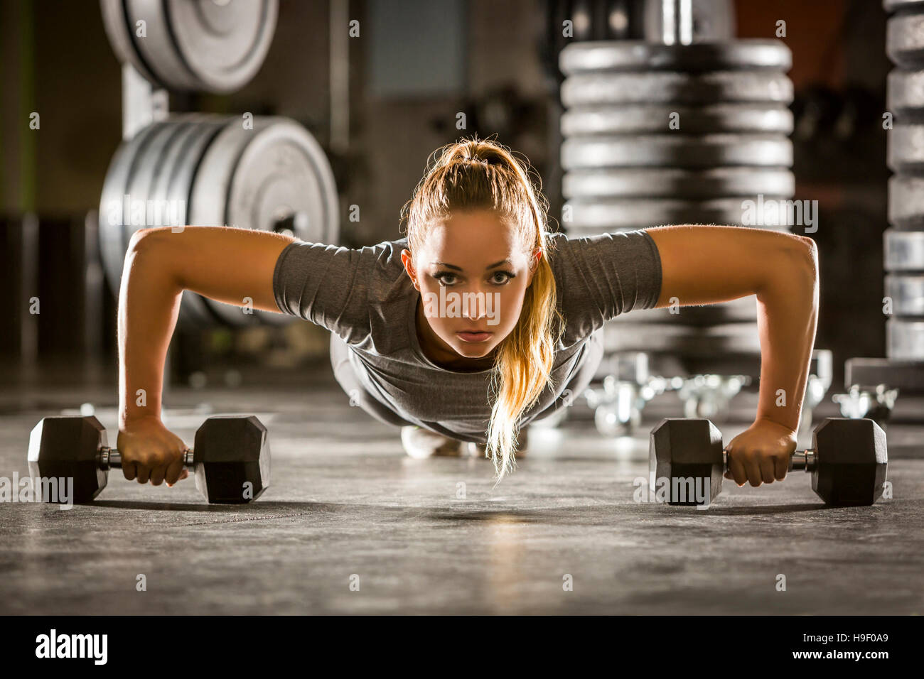 La donna caucasica facendo push-up utilizzando i pesi nella palestra Foto Stock