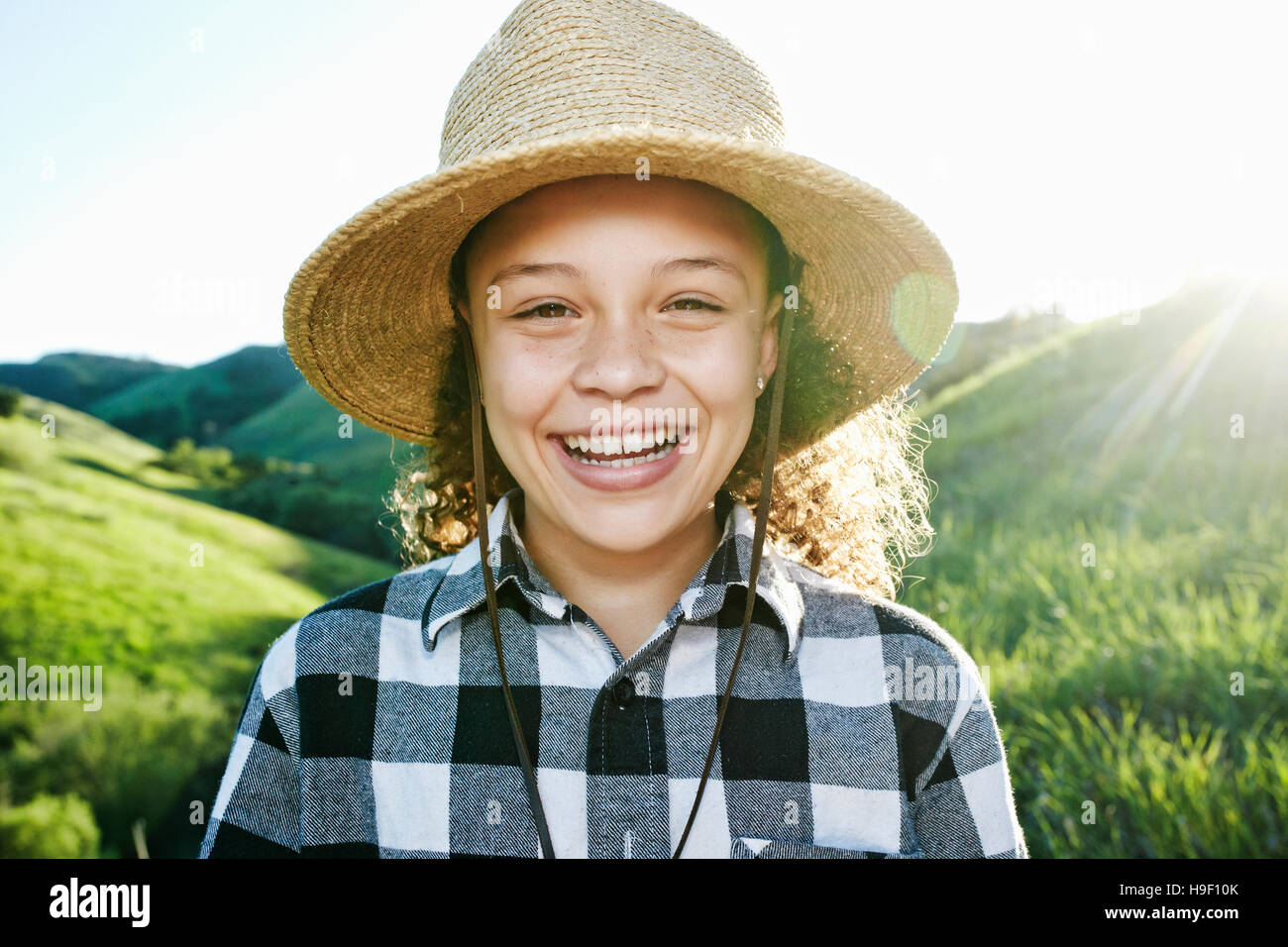Ragazza sorridente indossando hat sulla collina soleggiata Foto Stock