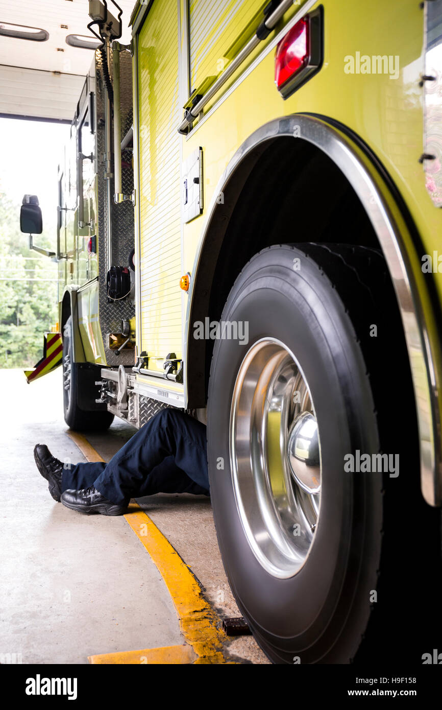 Fireman cinese la posa sotto il camion dei pompieri Foto Stock