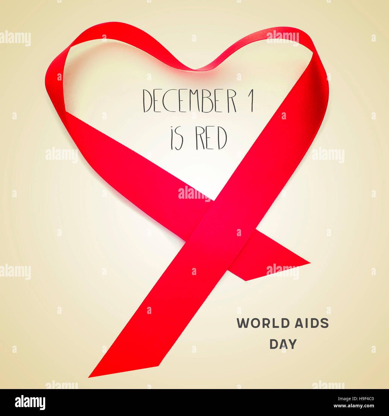 Un nastro rosso formando un cuore e il testo testo il 1 dicembre è rosso, giornata mondiale dell Aids su uno sfondo beige Foto Stock