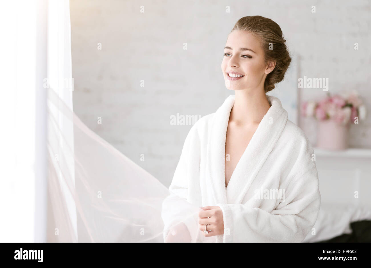 Sposa sorridente in piedi in colore bianco camera Foto Stock