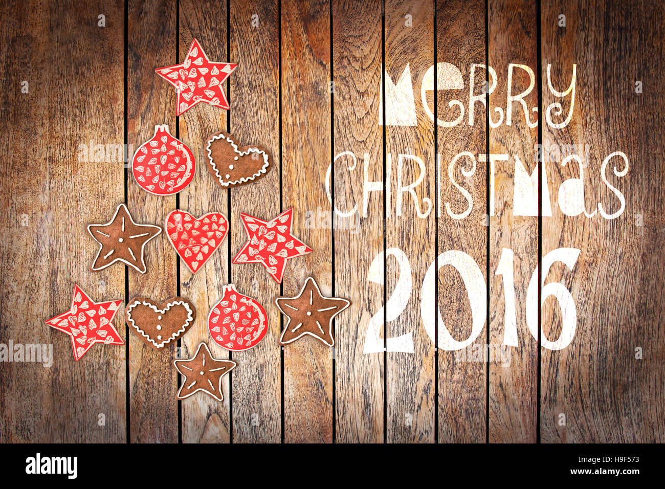 Natale biglietto di auguri 2016, ornamenti in stile rustico su tavole di legno sfondo creando la forma di un albero di Natale Foto Stock