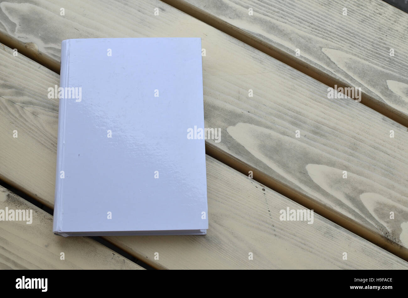 White hard cover libro su una panca in legno Foto Stock