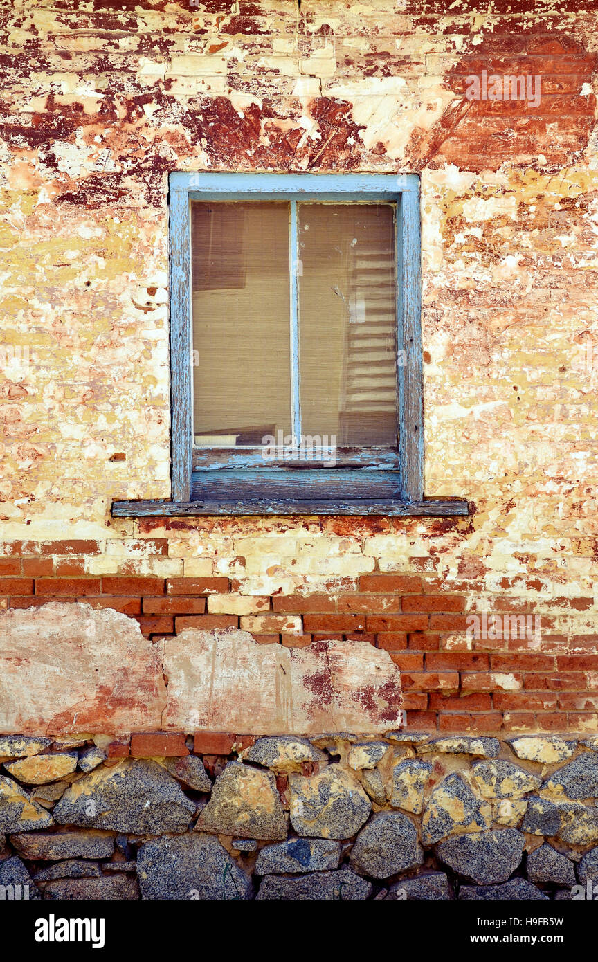 Vecchio rustico in legno di colore blu sul telaio di una finestra su edificio storico. Addolorato reso un muro di mattoni. Foto Stock