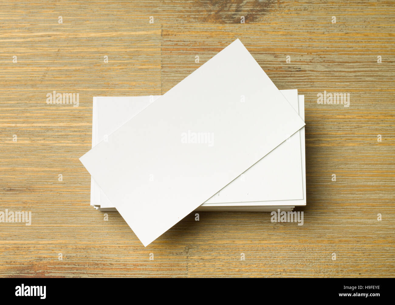 Pila di bianco non allineate le schede aziendali su un marrone tavolo in legno Foto Stock