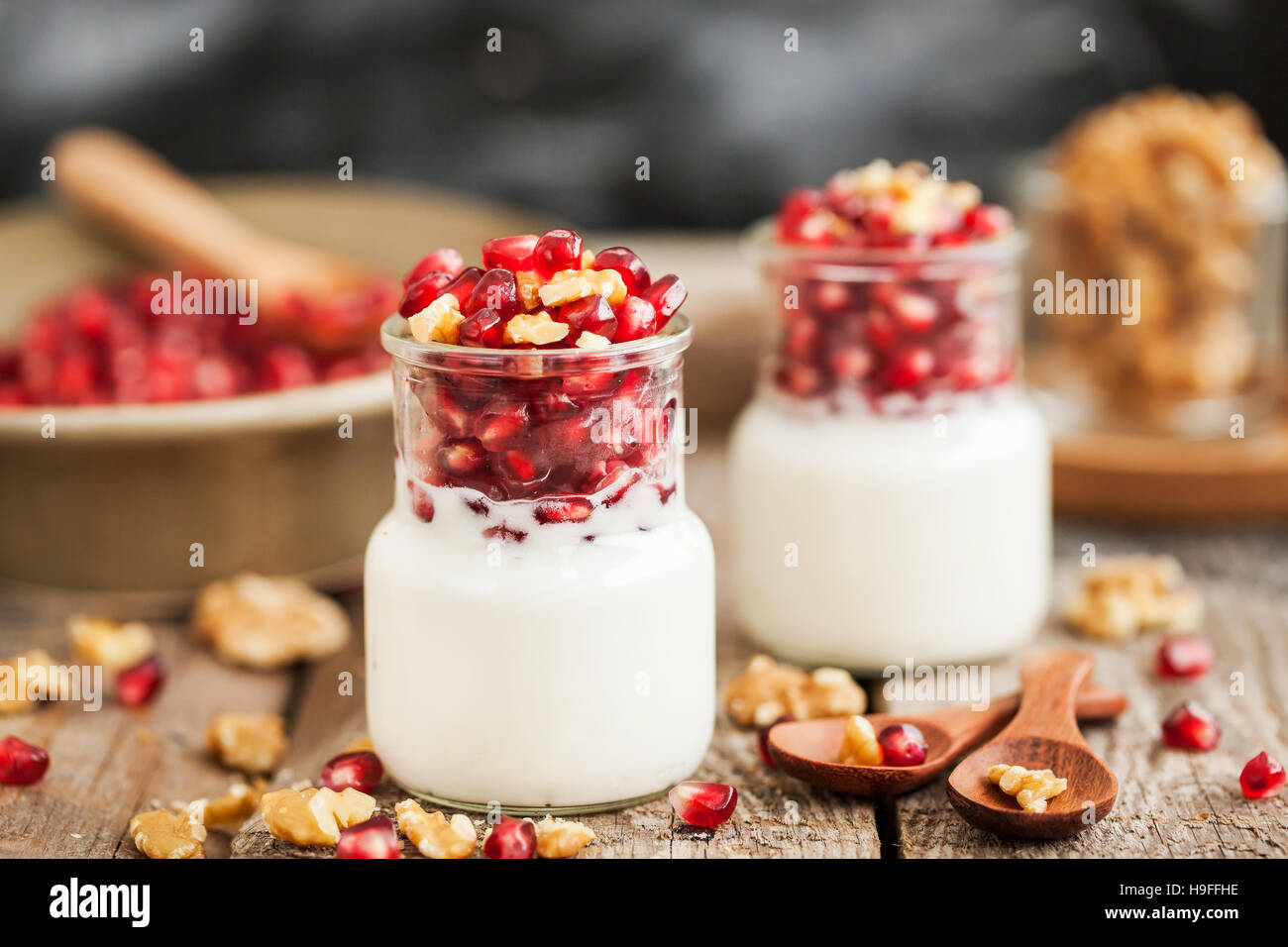 Fresco di yogurt bianco con i semi di melograno e noce in vasetti di vetro per la prima colazione Foto Stock