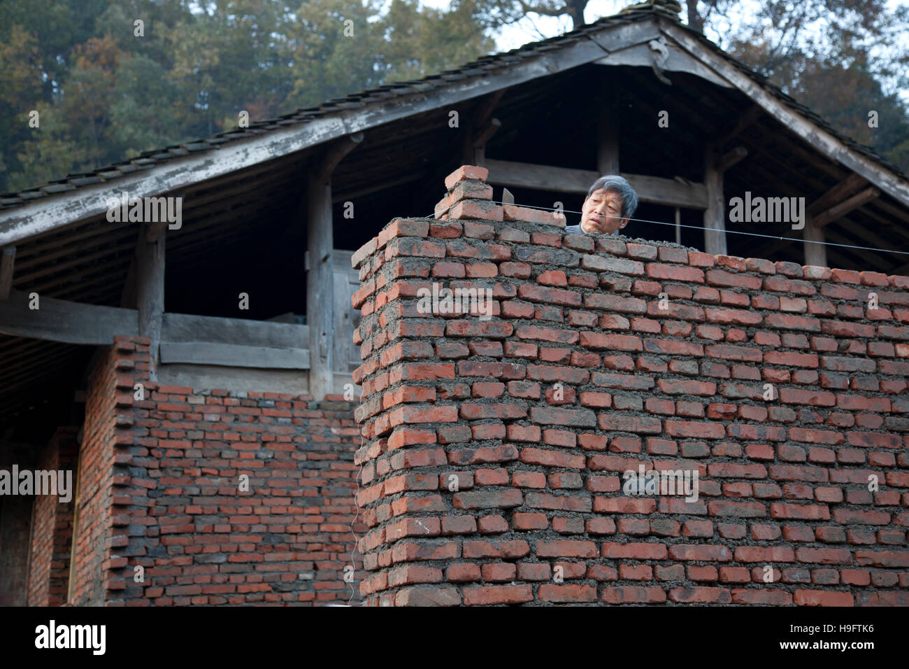 Un agricoltore a costruire la sua casa privata con mattoni e legno in un piccolo villaggio remoto nelle montagne della Cina occidentale. Foto Stock