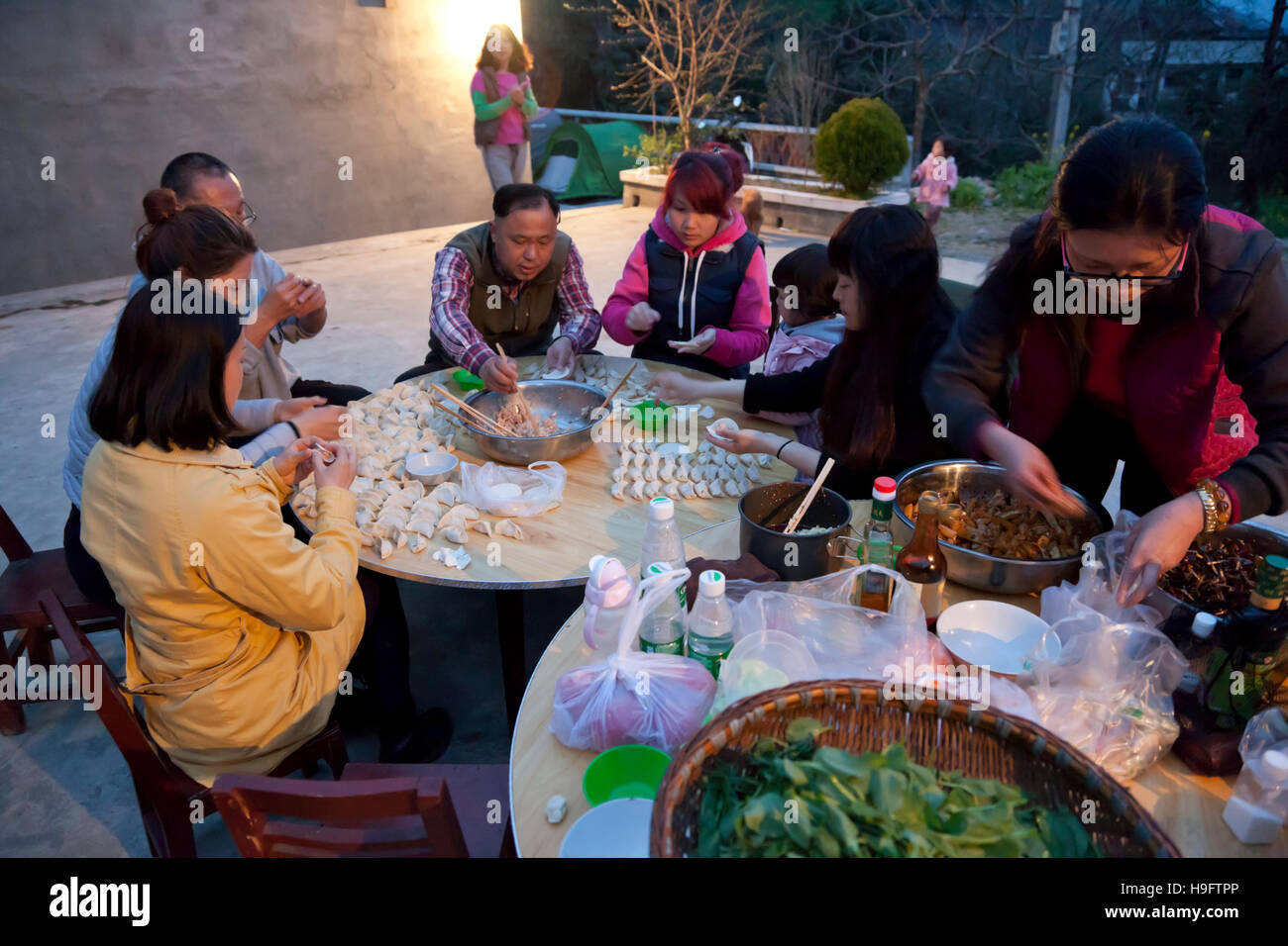 Un gruppo di amici fare gnocchi di fresco per cena durante una fattoria-soggiorno vacanza nelle montagne della Cina occidentale. Foto Stock