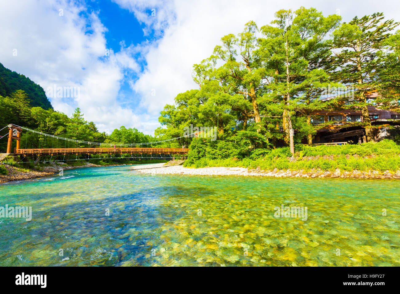 Blue sky si rompe attraverso le nuvole sopra il ponte Kappa-Bashi oltre le chiare acque alpine del Fiume di Azusa Al mattino in Kamikochi Foto Stock