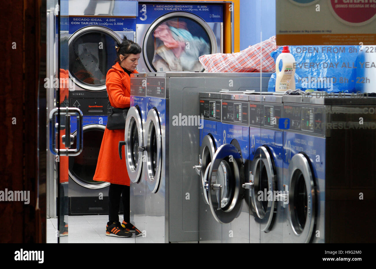 La donna in una lavanderia a gettoni in attesa per i suoi vestiti. Foto Stock