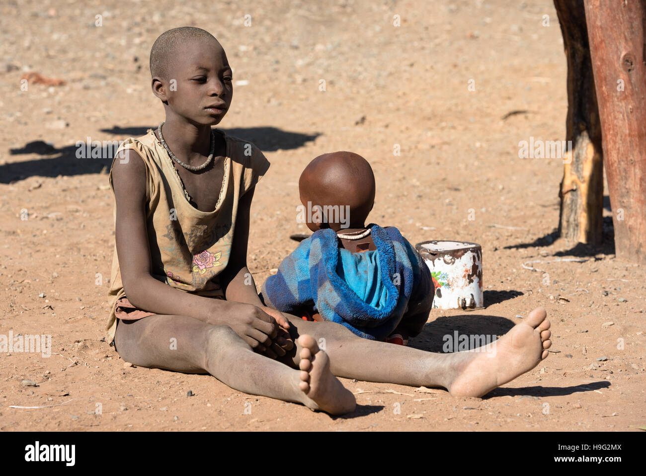 I bambini indigeni delle tribù Himba in abiti tradizionali stanno giocando nella sabbia al Kunene Regione della Namibia Foto Stock