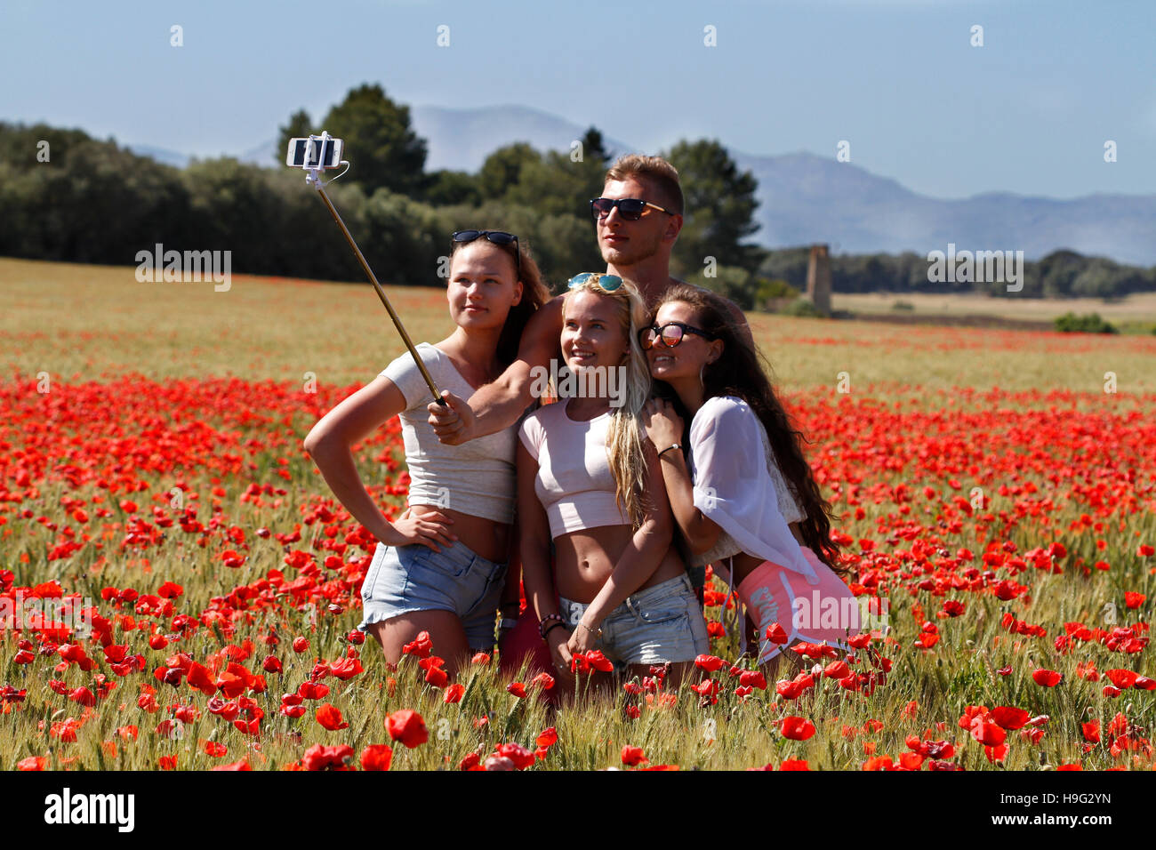 Gruppo di amici facendo un selfie in un campo di papaveri su una giornata di primavera a Maiorca nelle Isole Baleari in Spagna. Foto Stock