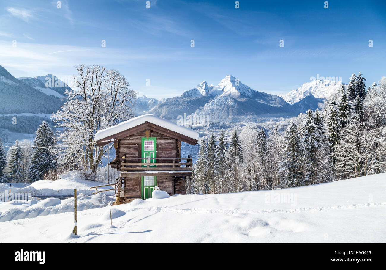 Winter Wonderland paesaggio di montagna delle Alpi con chalet di montagna tradizionale su una bella fredda giornata soleggiata con cielo blu Foto Stock