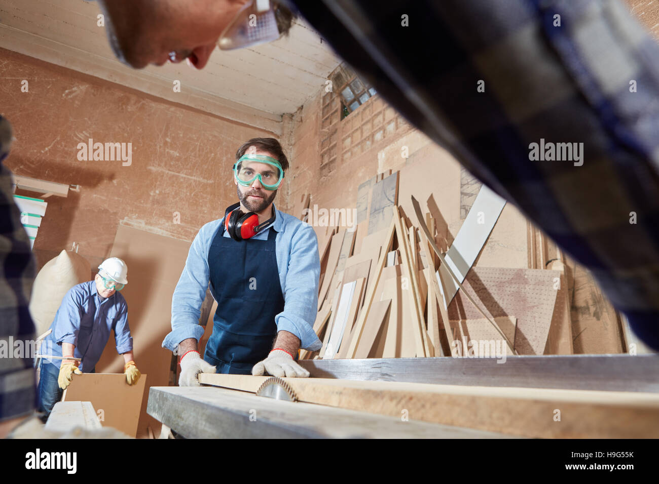 Carpenter il taglio di legno con la protezione del lavoro Foto Stock