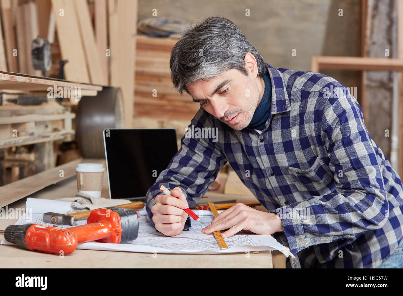 Artigiano di pianificazione e disegno nuovo design presso il negozio di falegnameria Foto Stock