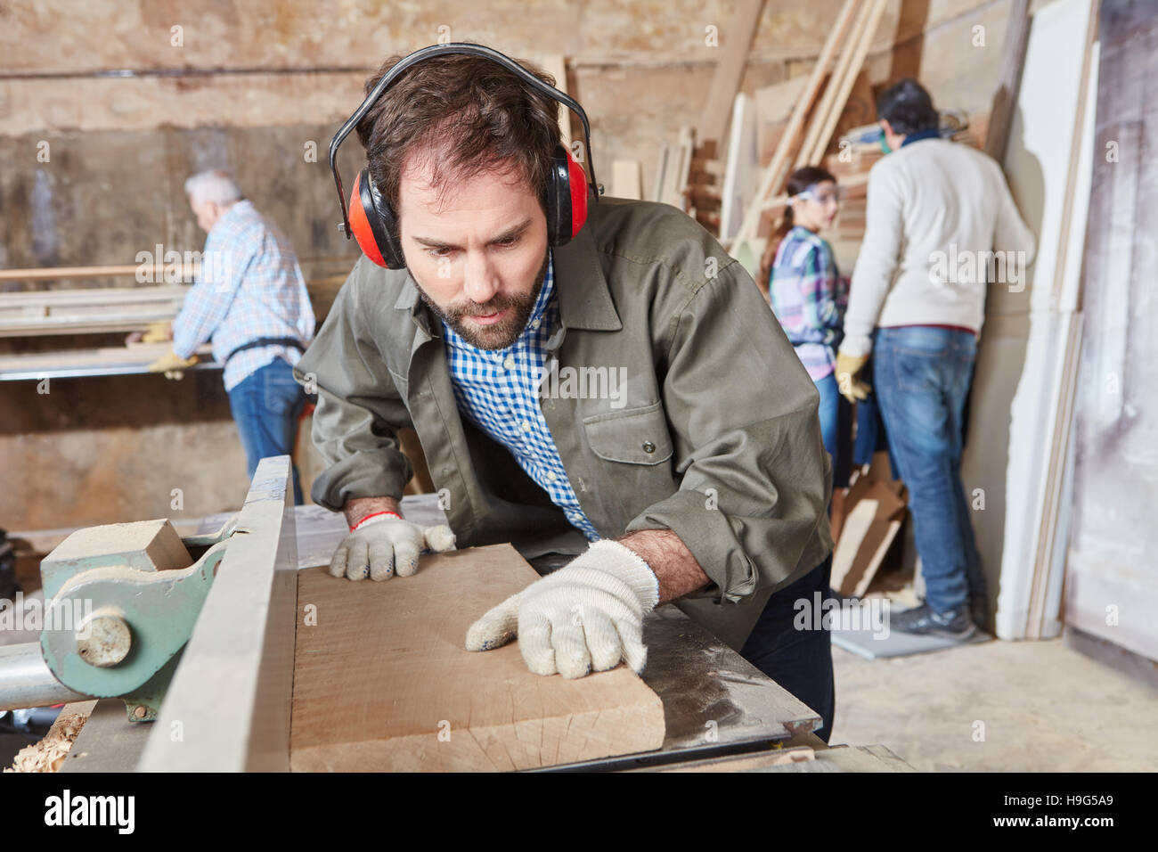 Negozio di falegnameria durante la lavorazione del legno con macchina levigatrice Foto Stock