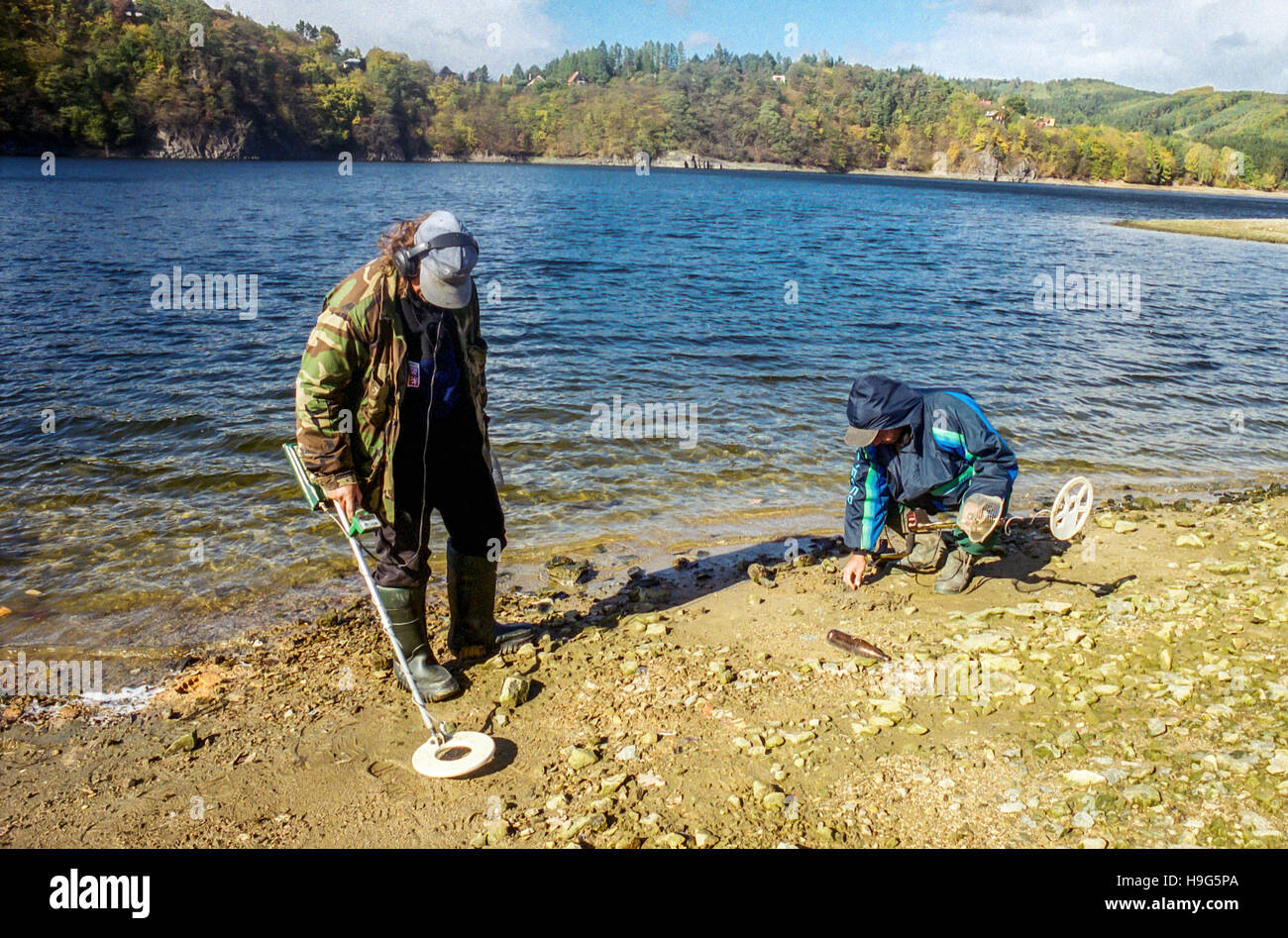 Gli uomini con il rivelatore di metalli cercare elementi sulla banca della diga Orlik, Repubblica Ceca Foto Stock