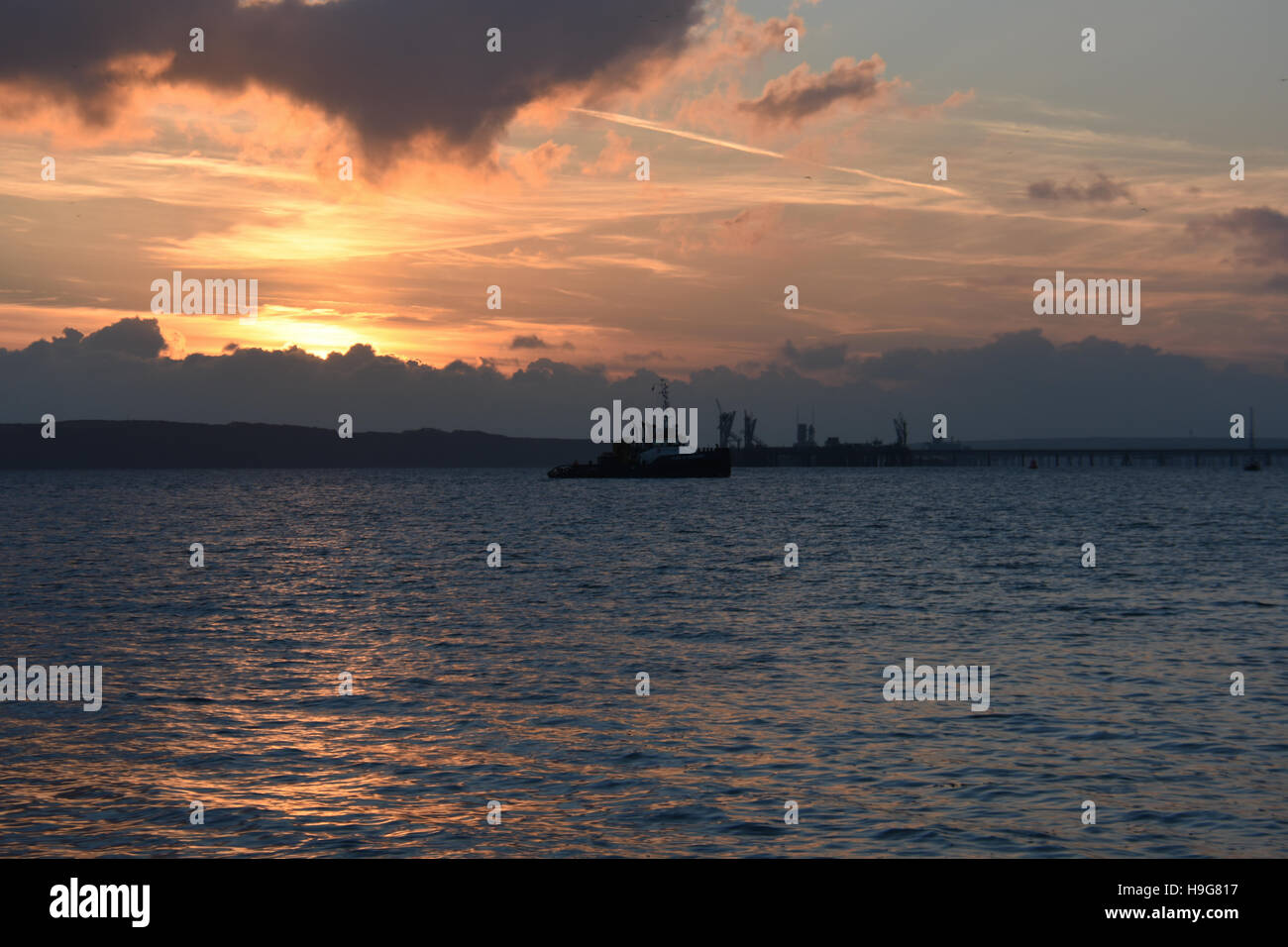 Rimorchiatore in attesa in mare calmo al tramonto per immettere Milford Haven dock Foto Stock