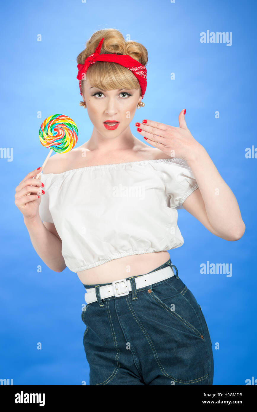 Pin up girl con la caramella lecca-lecca luminoso su sfondo blu Foto Stock