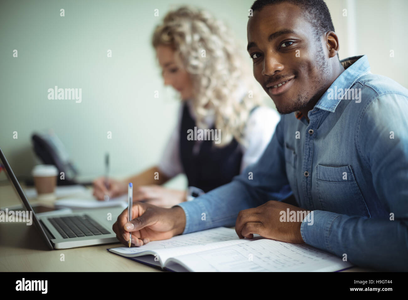 Business executive prendere appunti durante l'utilizzo di laptop Foto Stock