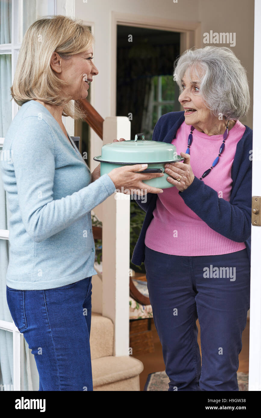 Donna portando pasto per anziani prossimo Foto Stock