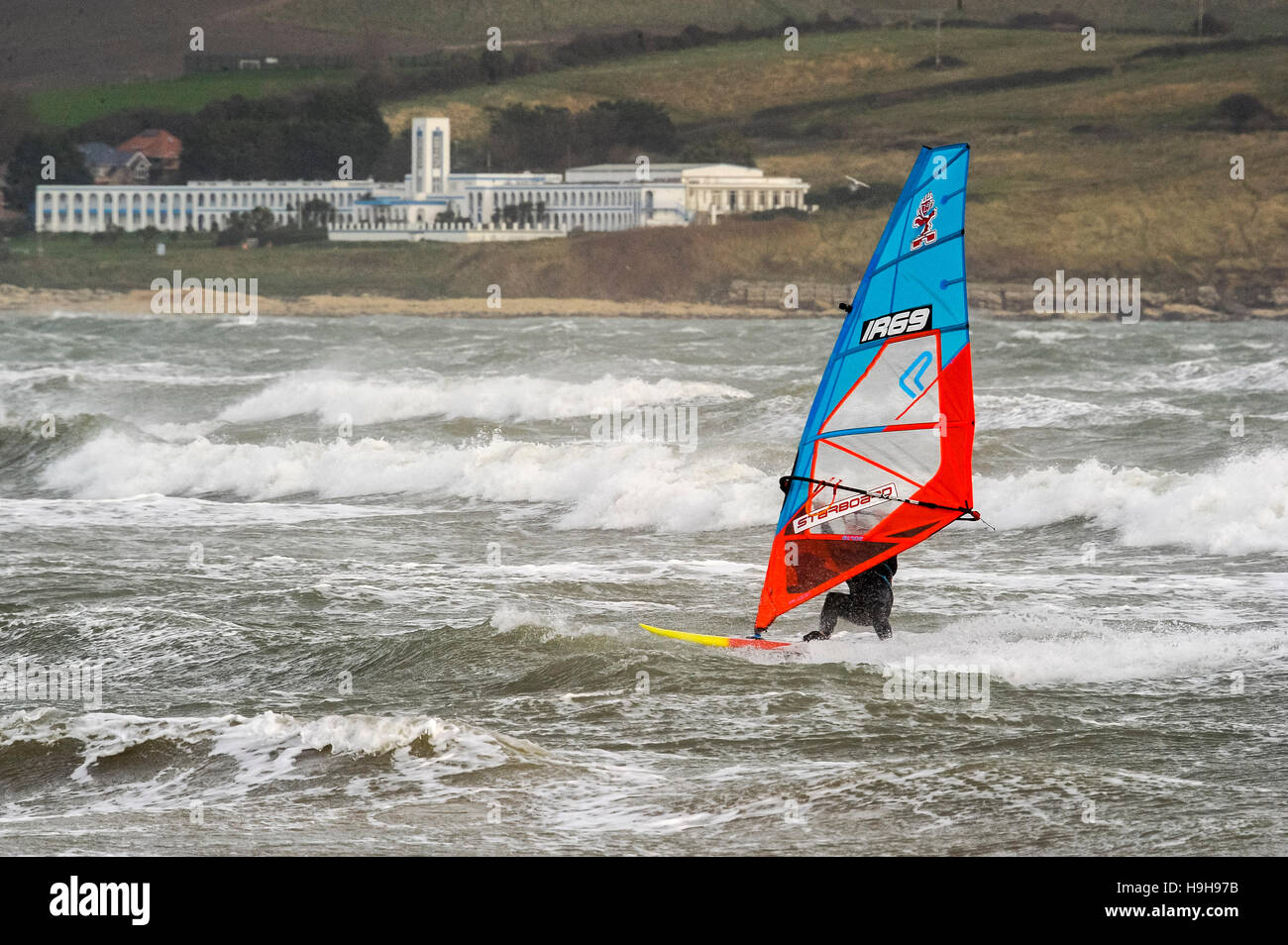 Weymouth Dorset, Regno Unito. Il 24 novembre 2016. Regno Unito Meteo. Una vista verso la Riviera Hotel a Bowleaze attraverso un mare di cavalli bianchi sulle onde ar mantecato fino da forti venti e mare mosso a Weymouth Beach nel Dorset che un windsurf è trarre pieno vantaggio. Foto di Graham Hunt/Alamy Live News Foto Stock