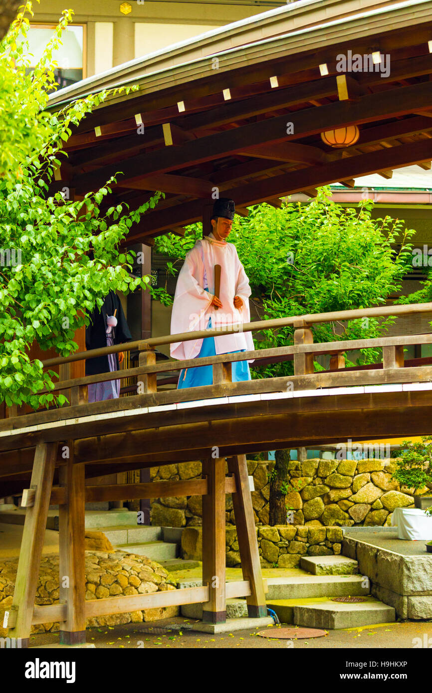 Lo Shintoismo sacerdote nella tradizionale tunica kannushi camminare sul suggestivo ponte di legno a Yushima Tenmangu santuario Foto Stock