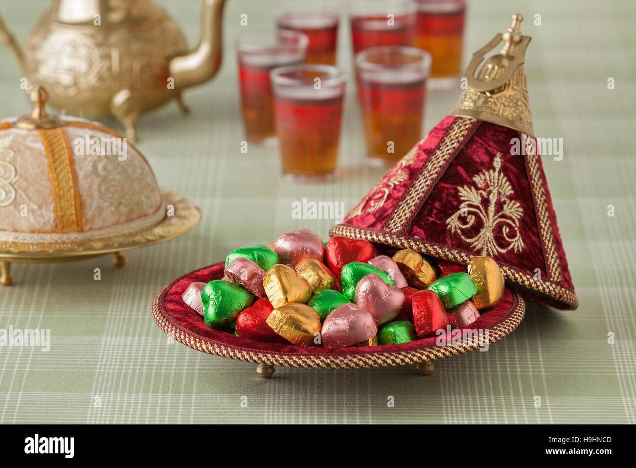 Marocchino dolci di festa in un rosso tajine e tè Foto Stock