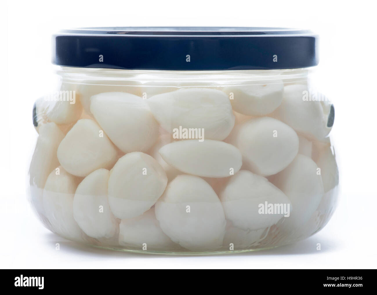 Aglio in un vetro vaso di storage con un blu scuro coperchio bianco, isolato su sfondo bianco Foto Stock