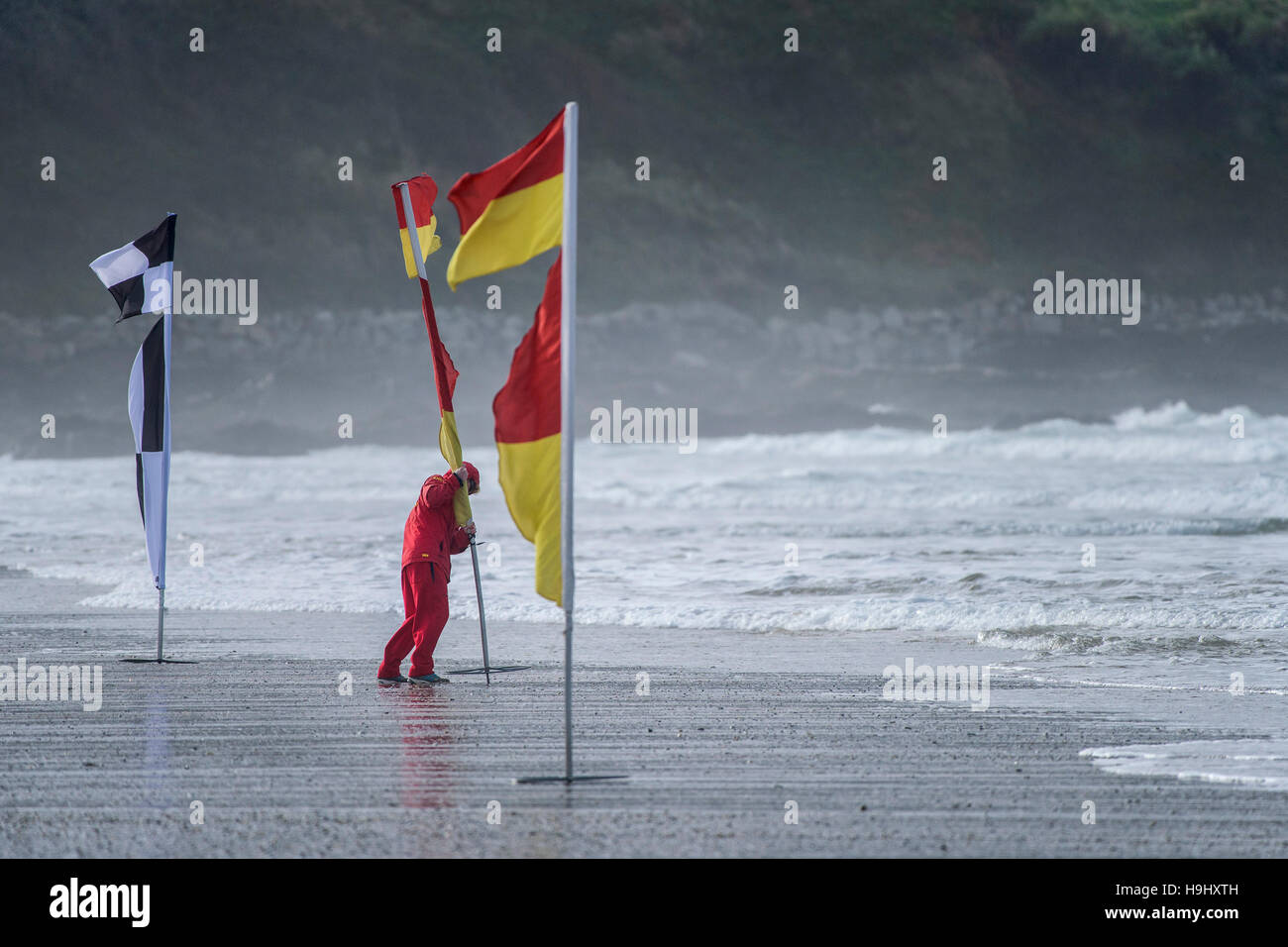 Un bagnino RNLI colloca un flag di sicurezza su Fistral Beach in Newquay, Cornwall. Foto Stock