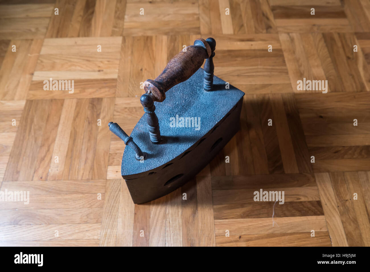 Un vecchio ferro pesante in piedi su un pavimento di legno Foto Stock