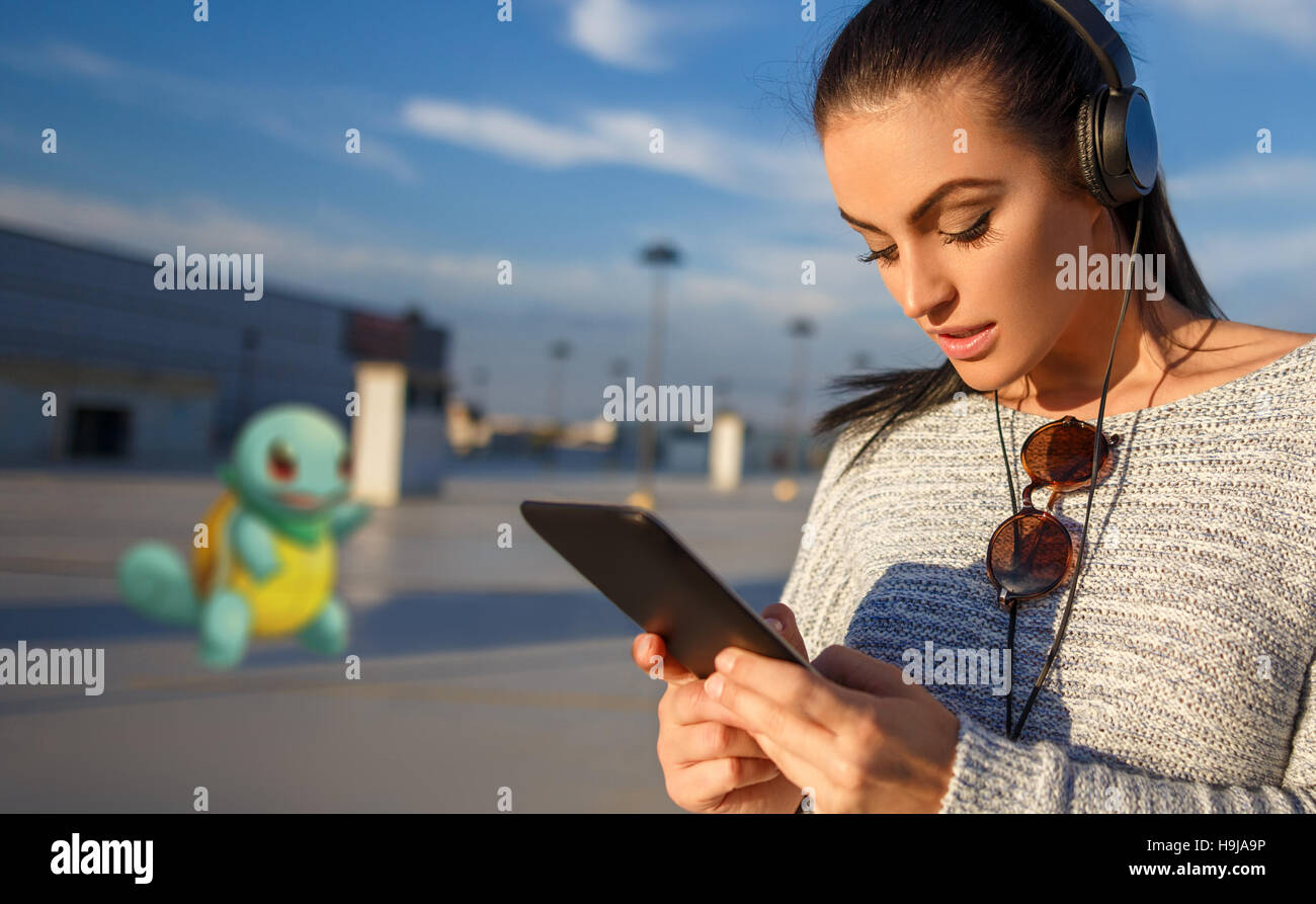 Giovane donna gioca pokemon vai su tablet outdoor Foto Stock