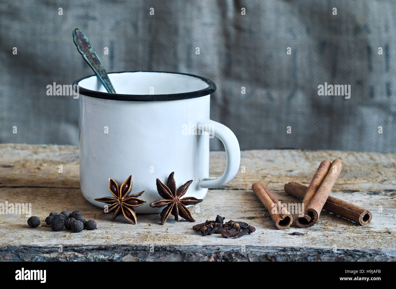 Ingredienti per la cottura Masala chai o vin brulé in bianco mug rustico con spezie su sfondo di legno per l'inverno e Natale. Alimentare la vita ancora Foto Stock