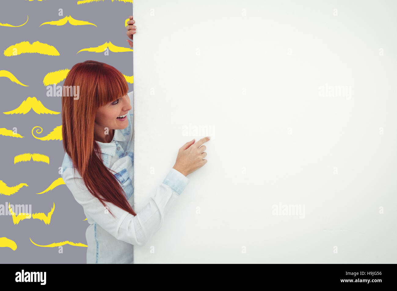 Immagine composita di sorridere hipster donna dietro una carta bianca Foto Stock