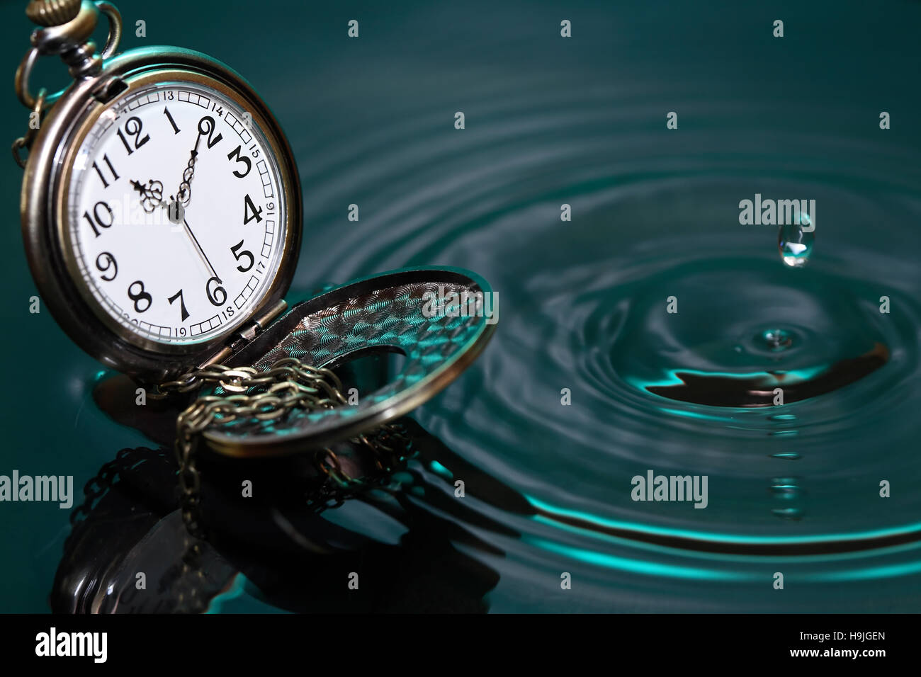 Concetto di tempo. Vintage orologio da tasca su acqua con la caduta della goccia Foto Stock