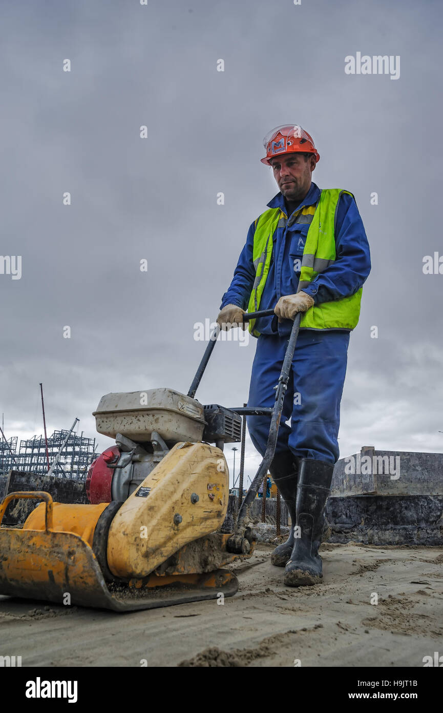 Builder lavoratore con piastra di vibrazione Foto Stock